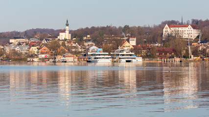 Obraz premium Starnberg, Bavaria / Germany - Mar 31 2020: Panorama of Starnberg. With church St. Joseph, Schloss Starnberg (Starnberg palace, on the right) and sightseeing boats. Lake in the foreground.