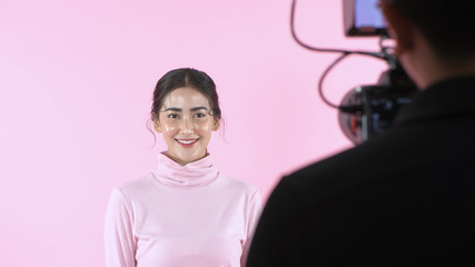 Beauty concept. A beautiful woman modeling in a studio on a pink background. 4k Resolution.