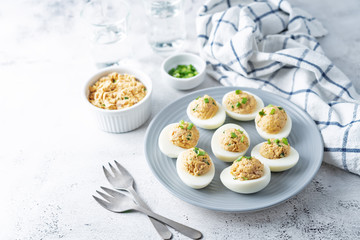 Canned Tuna deviled eggs with scallion on a light background