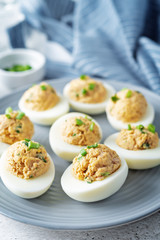 Canned Tuna deviled eggs with scallion on a light background