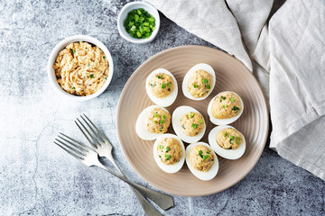 Canned Tuna deviled eggs with scallion on a light background