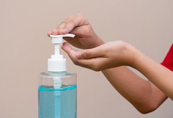 Asian girl kid using blue hand sanitizer gel in clear pump bottle , that use for killing germs, bacteria and viruses. Prevent the spread of germs and bacteria and avoid infections corona virus.