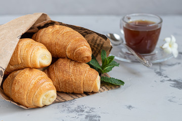 Croissants and coffee for breakfast with fresh raspberry jam on a light background. Decorated with a sprig of mint.