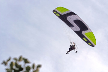 Powered paraglider flying in the blue sky. 
