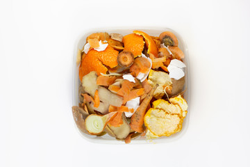 Food waste carrots, bananas, potatoes, oranges, onions, eggshells in a container on a white background. Top view. Flat lay. Waste for recycling.