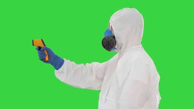 Temperature check on a corona virus Doctor in protective suit with pyrometer on a Green Screen, Chroma Key.