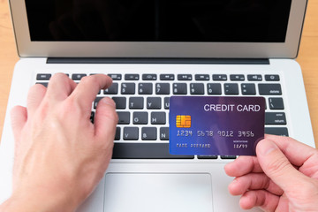 Obraz na płótnie Canvas Men hand holding credit card and type payment information on keyboard for order online shopping. Internet technology and Digital market place E-Commerce lifestyle concept, Purchase transaction.