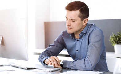 Businessman working with computer in modern sunny office. Headshot of male entrepreneur or company...