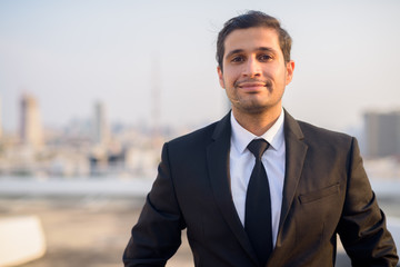 Young Persian businessman in suit against view of the city