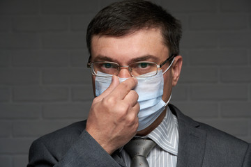 a man puts a mask on his face for antivirus individual protection - healthcare and medicine concept, prevention tips