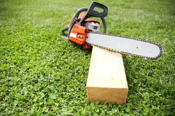  orange chainsaw on grass close up with copy space.