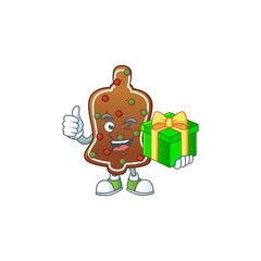 Smiley gingerbread bell cartoon character holding a gift box