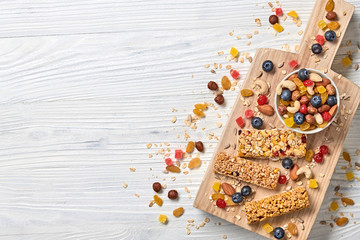 Energy healthy snack. Cereal granola bar with nuts and dry fruit berries. Fitness diet food. Protein muesli bars isolated on white wood. Sport oatmeal bar, top view
