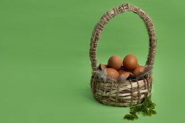 Chicken eggs in a basket on a green background. Wicker basket