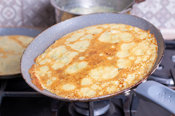 Thin pancakes are fried in a pan