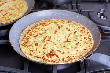 Thin pancakes are fried in a pan