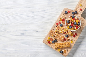 Fototapeta na wymiar Energy healthy snack. Cereal granola bar with nuts and dry fruit berries. Fitness diet food. Protein muesli bars isolated on white wood. Sport oatmeal bar, top view