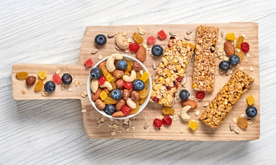 Granola bar with nuts and dry fruit berries. Energy cereal healthy snack. Fitness diet food. Protein muesli bars isolated on white wood. Sport oatmeal bar, top view