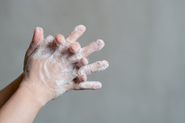 Closeup of person washing hands on gray background. Empty space for text