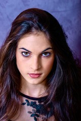Naklejka premium black hair woman portrait with brown eyes on a gray background , Caucasian ethnic group is looking into the camera with a serious expression on her face. White girl with long black hair and brown eye