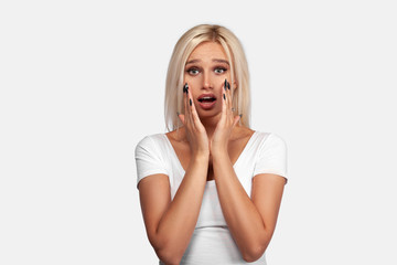 Fototapeta premium Young blonde woman wearing casual t-shirt standing over isolated white background surprised and shocked, excited and raising hands. Portrait of girl with perfect face and skin. Mockup.