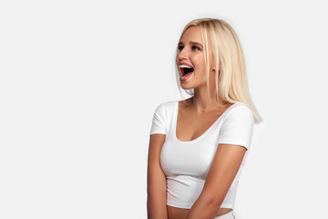Young blonde woman wearing casual t-shirt standing over isolated white background surprised and...