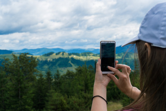 Girl makes photo of mountain landscape on phone