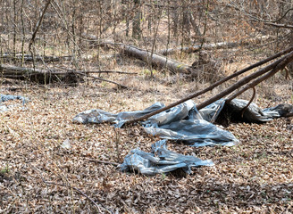 A dirty plastic and glass bottle left in the autumn forest. Plastic waste in the environment.