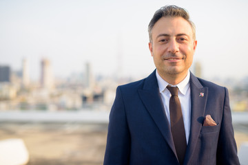 Face of happy mature businessman smiling against view of the city