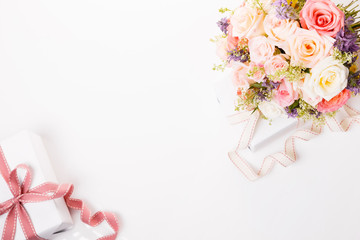 Delicate bouquet of pink roses flowers and gifts with ribbon on the table.