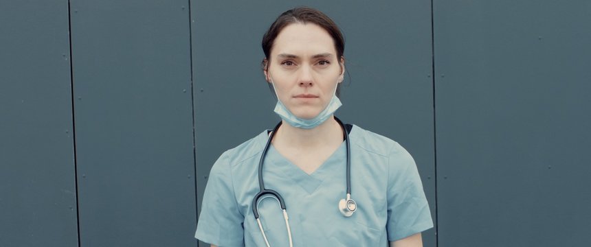 FRONT Portrait Of Tired Nurse Or Doctor Wearing Medical Mask Looking Into Camera. COVID-19, Coronavirus Pandemic