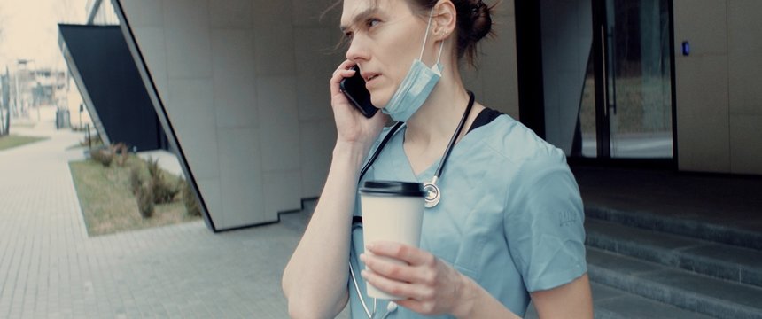 Portrait Of Tired Exhausted Nurse Or Doctor Having A Phone Call Outside In The Morning. COVID-19, Coronavirus Pandemic. ARRI Alexa Mini