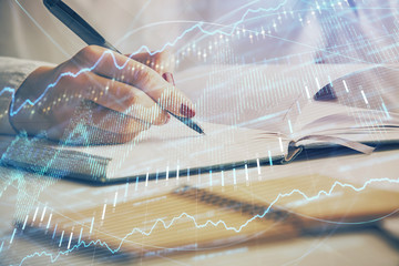 Multi exposure of woman's hands making notes with forex graph hologram. Concept stock market...