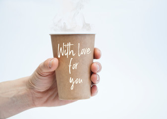 Paper cup in the hand. On a white background. Coffee and tea. With love for you.