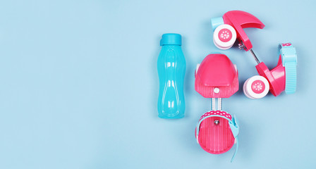 Pink roller skates for girls and a blue water bottle. Top view on a blue background with place for...