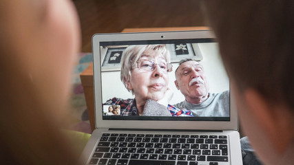 Young mom with son having a facetime video call with grandparents. Family connecting with their parents on webcam. Modern technology connecting people of all ages concept.