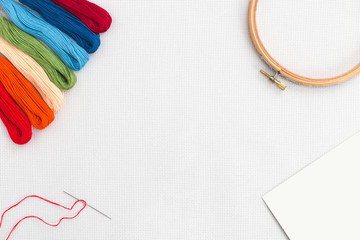 Embroidery hoop, needle and different color of thread for sewing lying on a white background. Set...
