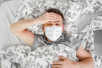 masked male lies at home bed and sick. stay home
