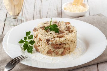 Wild mushroom risotto with parsley and parmesan on a white wooden background
