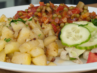 Kartoffelsalat mit sautierten Erbsen und Tomaten sowie frischer roher Gurke und Champignon