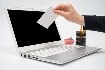 Online voting concept with a man with a ballot in hand putting a ballot toward the computer monitor.