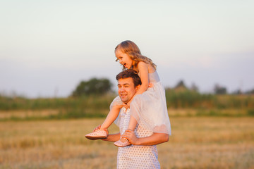 dad ride daughter on shoulders in stubble field 