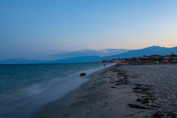 Sea coast and beach at night. Houses along the shore. Pieria, Greece.