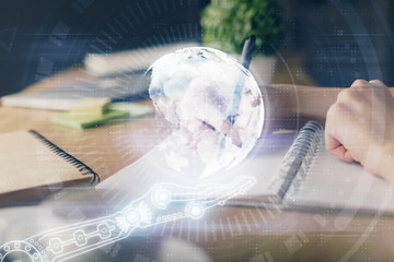 Double exposure of hands making notes with world map hologram and data theme icons. Concept of international network data.