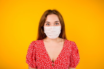Portrait of a beautiful Slavic girl in a protective medical mask on a yellow background