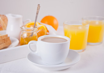 Cup of coffee or tea, bread toast with orange jam, glasses of orange juice on the white background. Breakfast concept.