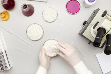 Top view of a desk in a chemistry lab with chemicals, pipette and microscope