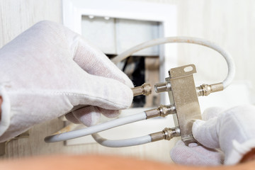 Worker inserts connector of a TV antenna coaxial cable to a splitter.