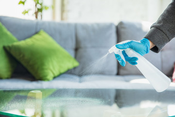 Essential goods during epidemic - prevention and protection of coronavirus COVID-19 spreading. Hand in gloves disinfecting surfaces with sanitizer at home. Cleaning against pneumonia virus.