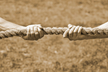 Two men's hands pull the rope each in his own direction. The concept of dispute, conflict and...
